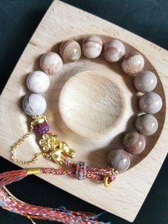 This beautiful bracelet has 12 pink-grey-toned pastel round beads. Number 12 symbolizes the twelve links of dependent origination in Buddhism, linking the circle of life. The beads used are made from fully natural and authentic Alashan agate. The metal parts are copper based gold plated alloy. The bracelet is not stretchy, but it has a fully handmade adjustable weaved strap, so it will fit most wrist sizes. As a reference, my wrist (as shown in the picture and video) is 16cm. The Alashan agate i Adjustable Beige Bracelet With Round Beads, Handmade Beige Bracelets With Round Beads, Beige Round Beads Jewelry As Gift, Beige Round Beads Jewelry For Gift, Beige Round Beads Jewelry Gift, Beige Round Beads Bracelets As Gift, Beige Round Bead Bracelets For Gifts, Adjustable Round Beige Bracelets, Adjustable Beige Bracelets