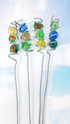 four metal pins with different colored glass balls on them