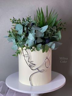 a white cake decorated with greenery and a stethoscope in the shape of a woman's face