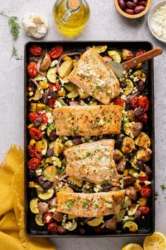 salmon and vegetables on a baking sheet with olives