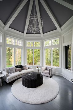 Modern Sunroom in Shades of Gray and White White seating group and a white circular carpet are placed on the gray wooden floor, while the wall surfaces and window joinery are also used in white, the colors used in the roof are also gray and white. Octagon Sunroom, Sunroom Ideas Modern, Sunroom With Fireplace, White Sunroom, Grey Wooden Floor, Sunroom Windows