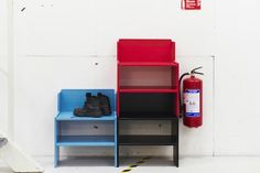 a fire extinguisher sitting next to three shelves with shoes on them and a red fire extinguisher in the background