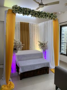 a bed with white sheets and yellow drapes in a room decorated for a wedding