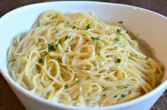 a white bowl filled with pasta and garnished with parsley