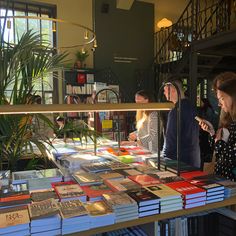 people are looking at books on display in a book store while others stand around the table