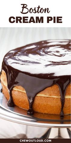 boston cream pie on a cake plate with chocolate sauce drizzled over the top