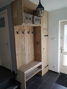 a wooden bench with two baskets on the top and one shelf above it, in front of a door