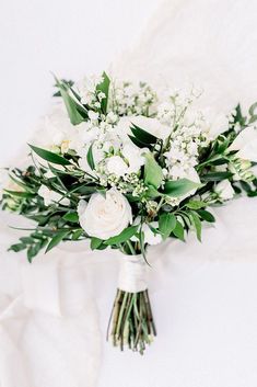 a bridal bouquet with white flowers and greenery