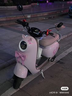 a pink scooter is parked on the side of the road with a bow