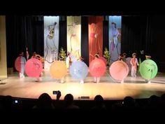 a group of people standing on top of a stage in front of an audience with balloons