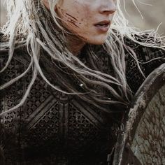 a close up of a person with long hair and white hair wearing a viking outfit