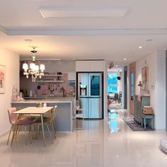 an open kitchen and dining room with white tile flooring, chandelier lights and modern furniture