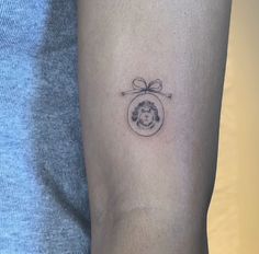 a woman's arm with a small tattoo of a dog in a round frame