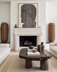 a living room with white couches and a table in front of a fire place