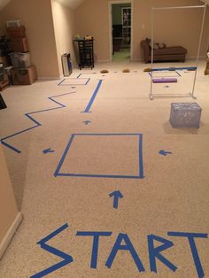 a room with blue tape on the floor that says start and arrows pointing in different directions