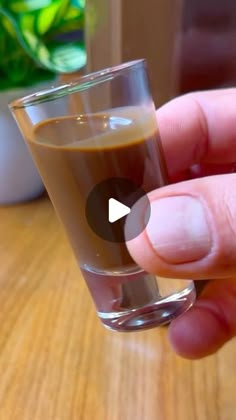 a hand holding a shot glass filled with liquid