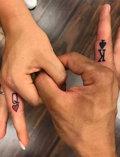 two people with matching tattoos on their fingers holding each other's hands and pointing to the opposite direction