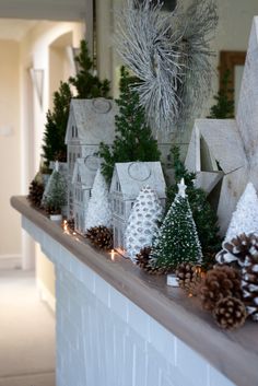 a mantle with christmas trees and pine cones on it in front of a house decorated for the holidays