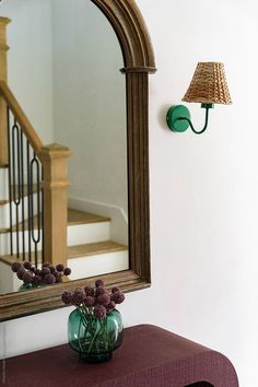 Entryway with gilded mirror, sconces, flowers, and suitcases