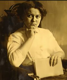 an old photo of a woman sitting in a chair with her hand on her chin