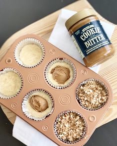 some cupcakes with peanut butter in them on a wooden tray next to a jar of peanut butter