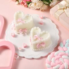 two heart shaped cookies sitting on top of a white plate next to pink and blue candy