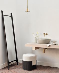 a white sink sitting next to a mirror and a black stand with a bowl on it