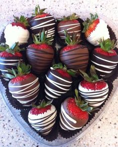 chocolate covered strawberries are arranged in a heart - shaped tray on the counter top