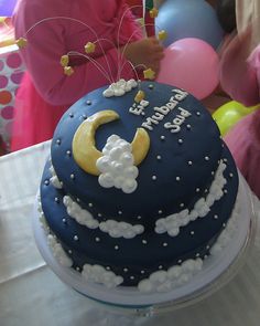 a birthday cake with the moon and stars on it is sitting on a table in front of some balloons