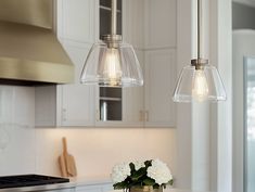 two clear glass pendant lights hanging over a kitchen counter