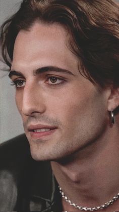 a close up of a person wearing a necklace and pearls on his neck, looking at the camera