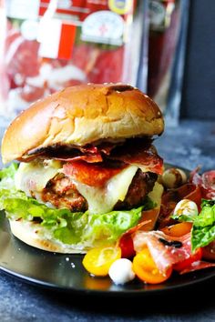 a sandwich with meat, lettuce and tomatoes on a plate next to a salad