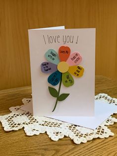 a card that says i love you and has a flower on the front with words in different colors