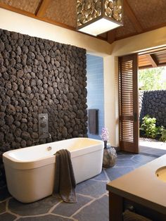 a bathroom with a stone wall next to a bathtub