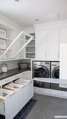 a washer and dryer in a room with white cupboards on the wall