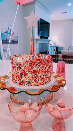 a birthday cake with sprinkles on it sitting on a table next to other desserts