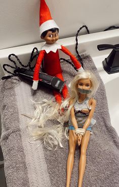 two dolls sitting on top of a towel next to a hair dryer and comb