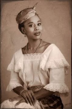 an old black and white photo of a woman in a dress with pearls on her head