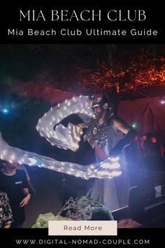 a man holding a rope in the air with lights on it and people standing around him