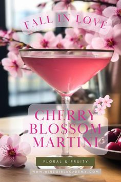 a pink cocktail with cherry blossoms in the background and fall in love written on it