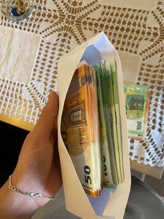 a person is holding up some money in a paper bag that they are folded into