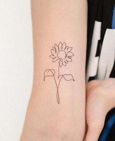 a woman's arm with a small tattoo of a sunflower on the left side