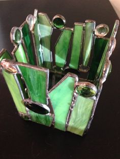 a green glass vase sitting on top of a table