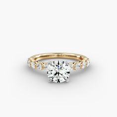 a yellow gold engagement ring with round brilliant cut diamonds on the band and side stones