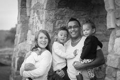 a black and white photo of a family posing for the camera in front of an old stone building