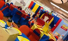 a room filled with tables and chairs covered in blue, yellow and red cloths