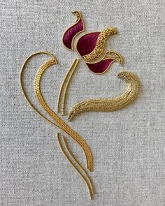 a gold and red flower brooch on a gray fabric background with the word love written below it