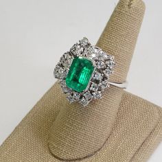 This Platinum Vintage Ring has a stunning large emerald as its center piece. The emerald has strong intense green color and shimmers as you move the piece around! The emerald is set with prongs and on all sides surrounded with sparkly high quality eye clean diamonds in flower petal shapes. There are a total of 57 round brilliants for a total of 2 carats. The ring is a size 7.5. This ring is a great collector's piece with its sparkly flowery design and good quality large emerald! Ring Size: 7.5 T Exquisite Green Emerald Platinum Ring, Emerald Ring With Halo Setting In Platinum, Green Emerald Platinum Ring With Halo Setting, Green Emerald Ring With Halo Setting In Platinum, Gia Certified Green Emerald Ring In Platinum, Gia Certified Green Emerald Platinum Ring, Green Baguette-cut Platinum Jewelry, Green Platinum Emerald Ring For May Birthstone, Exquisite Green Emerald Ring With Brilliant Cut