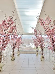 an indoor wedding ceremony with pink flowers on the trees