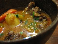 a bowl filled with meat and vegetables on top of a wooden table